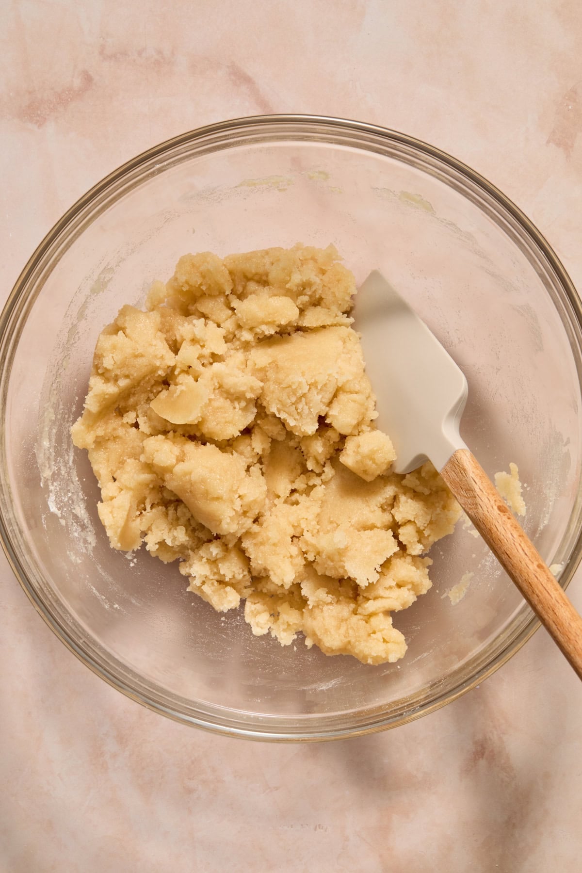 Cobbler topping mixture in glass mixing bowl with spatula.