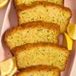 Slices of lemon glazed lemon zucchini bread on plate with lemon wedges.