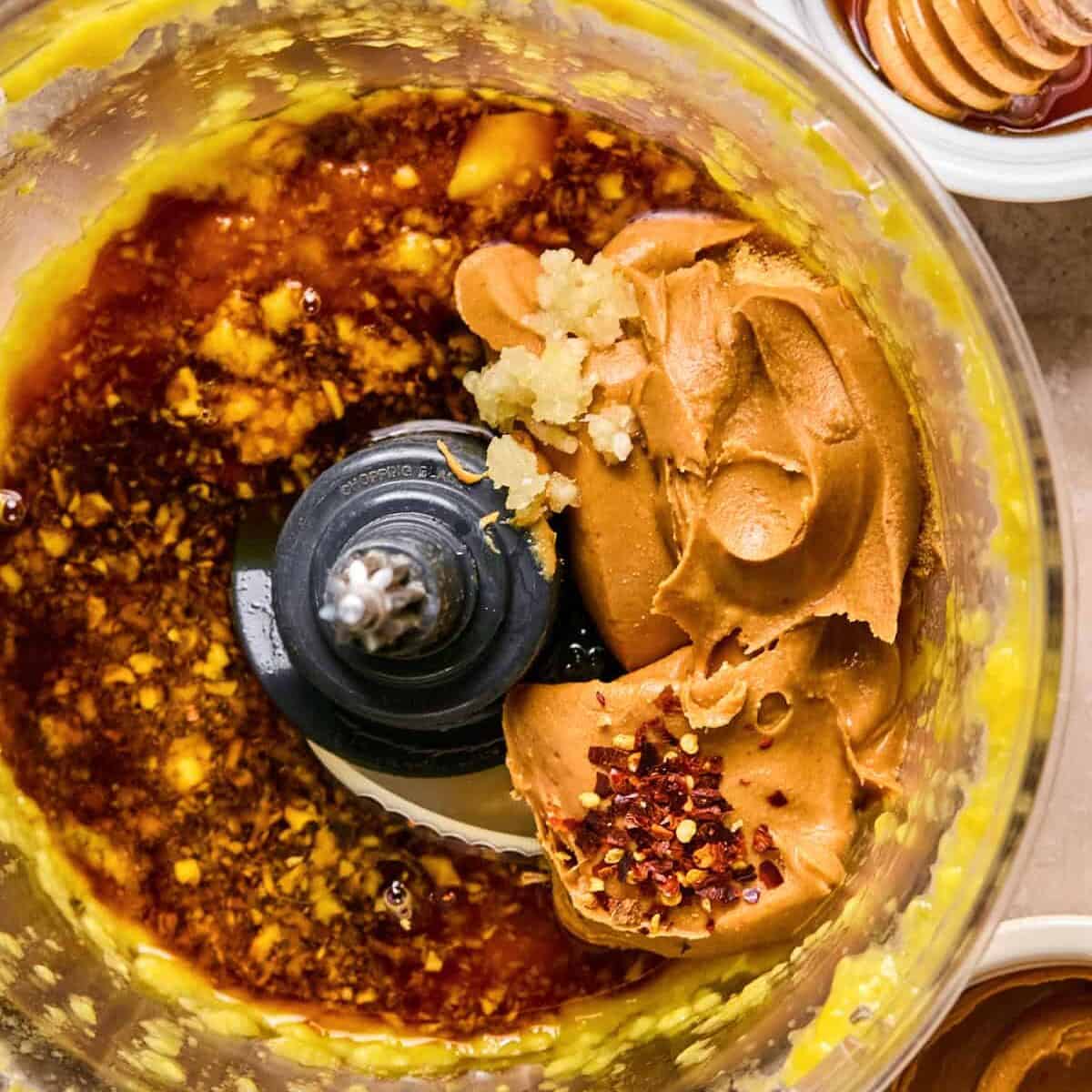 Peanut butter, soy sauce, red pepper and other ingredients added to mango in food processor.