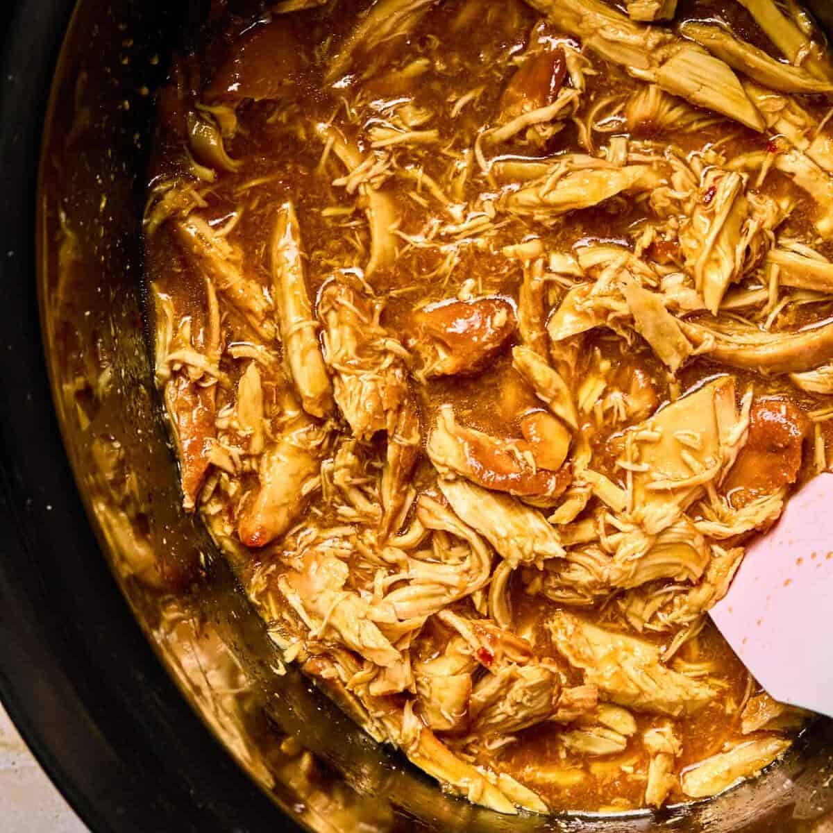 Crockpot honey sriracha shredded chicken in pot.