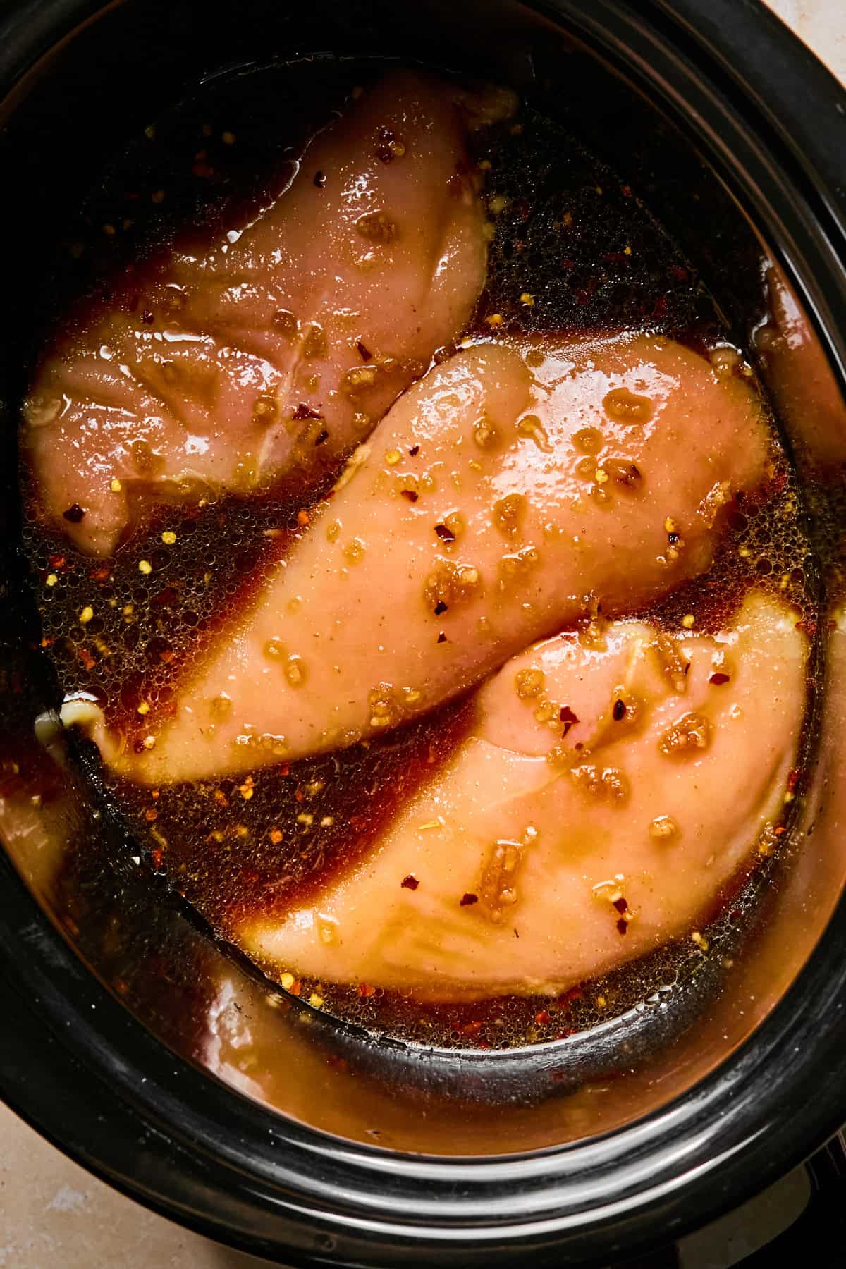 Honey garlic sriracha sauce poured over chicken breasts before cooking.