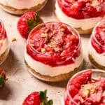 Dessert glass with layered strawberry topped cheesecake cups.