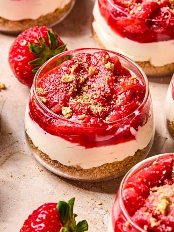 Dessert glass with layered strawberry topped cheesecake cups.