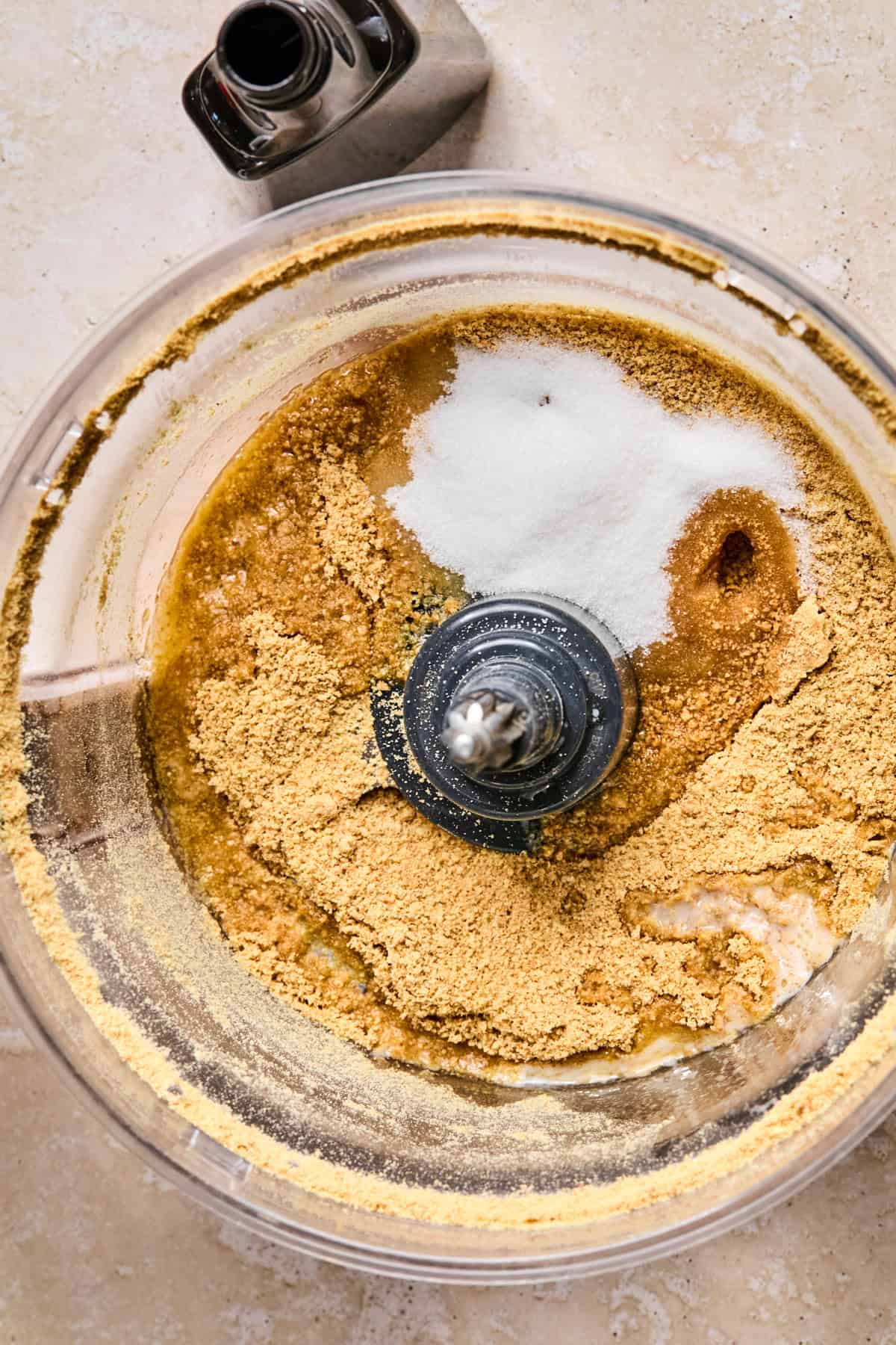 Sugar and butter added to crushed graham crackers in food processor.