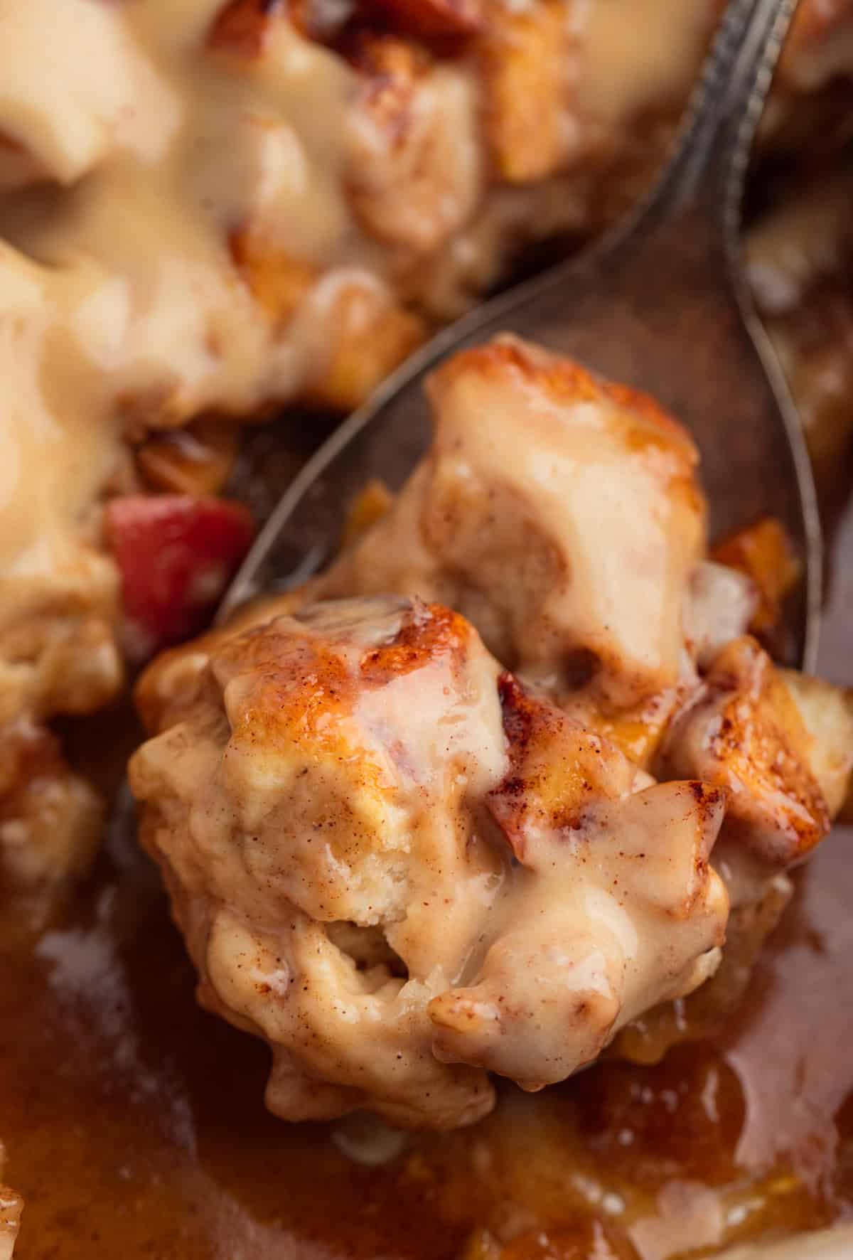 Apple cinnamon biscuit bake in pan with spoonful of dish.