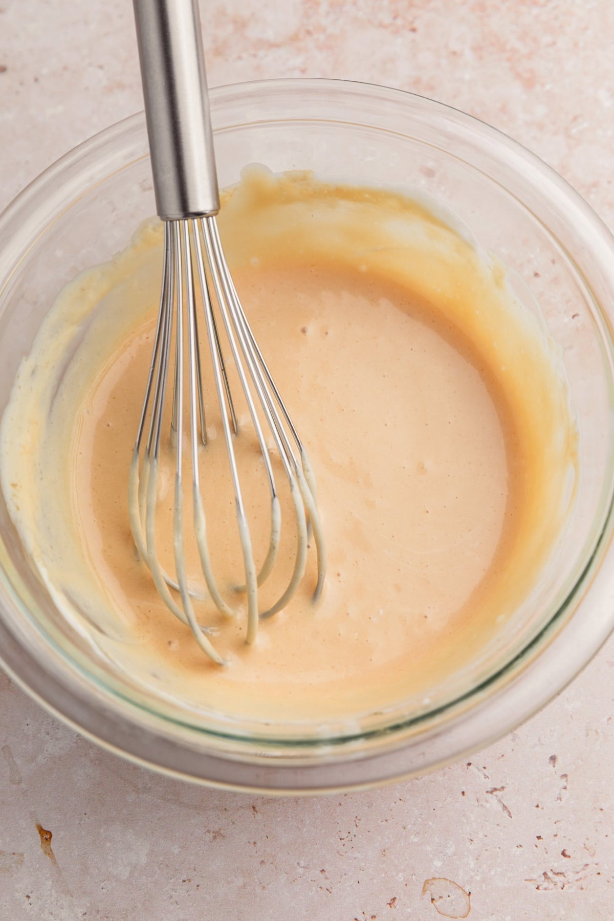 Brown sugar cream cheese icing in bowl with whisk.
