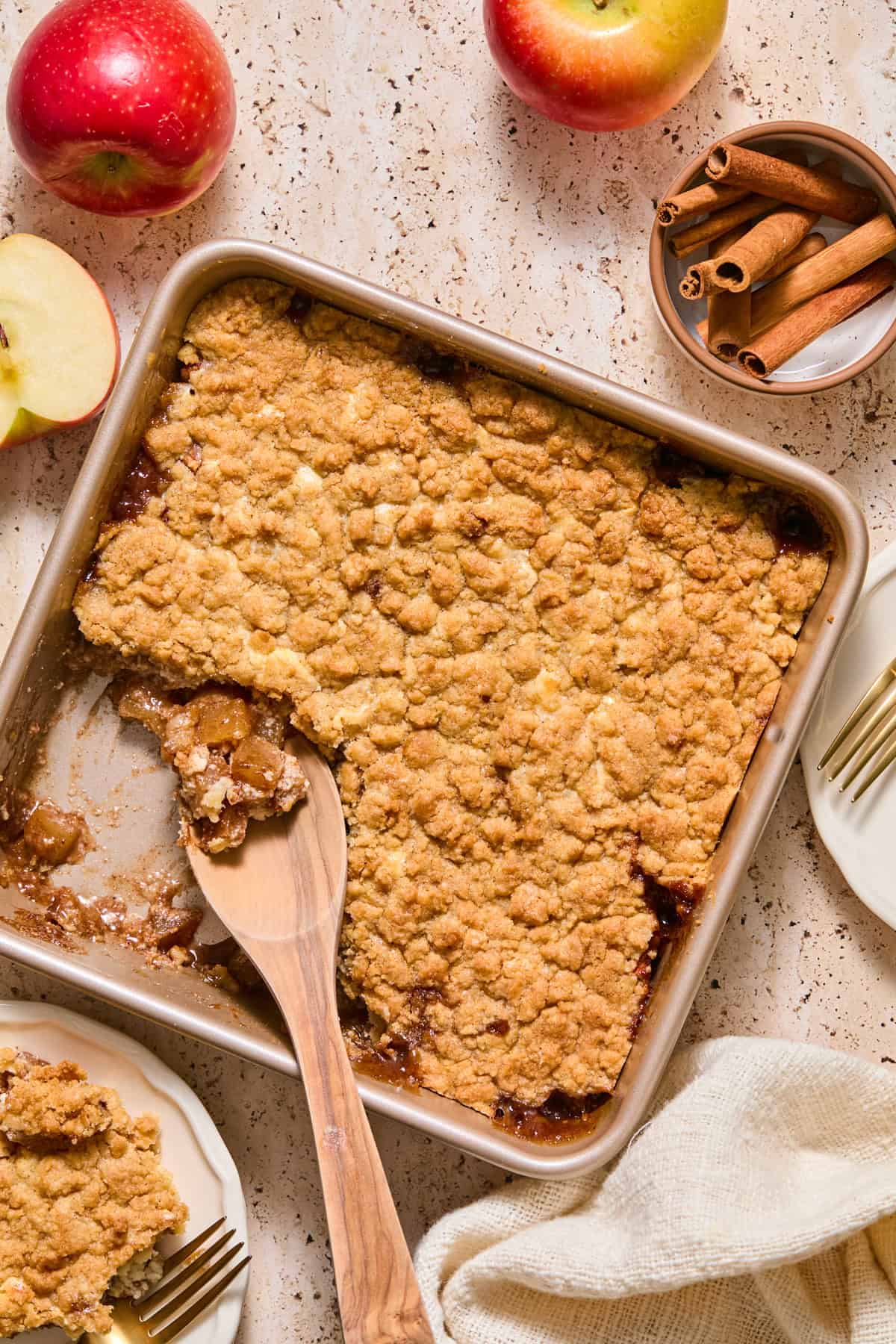 Apple cheesecake cobbler in pan with wood spoon.