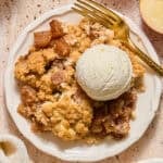 Apple cream cheese cobbler on plate with scoop of vanilla ice cream.