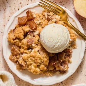 Apple cream cheese cobbler on plate with scoop of vanilla ice cream.