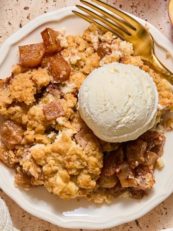 Apple cream cheese cobbler on plate with scoop of vanilla ice cream.