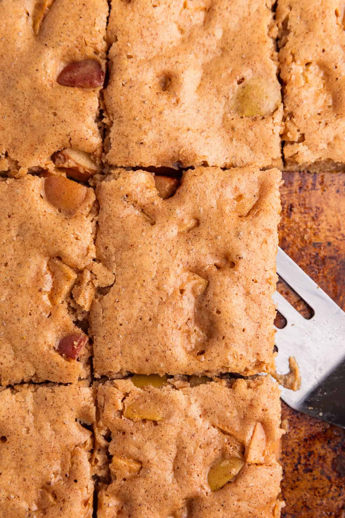 Sliced sheet pan apple cinnamon protein pancakes with spatula.