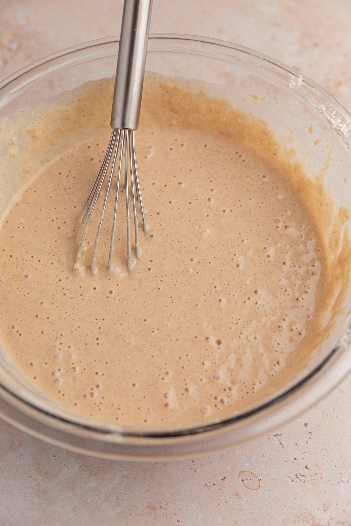 Dry ingredients mixed into wet in pancake batter in bowl.