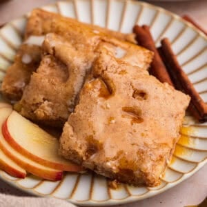 Stack of apple cinnamon sheet pan protein pancakes topped with maple syrup.