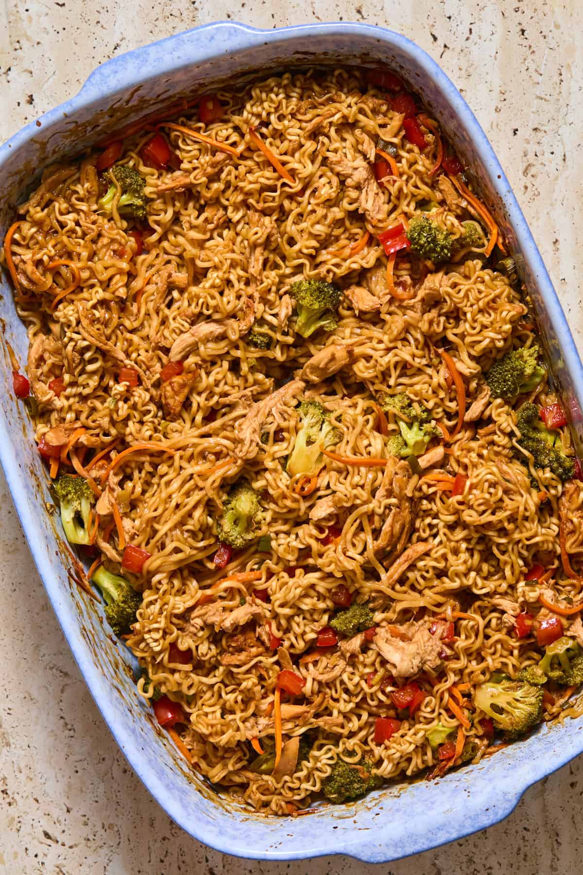 Baked chicken and vegetables with ramen noodles in baking pan.