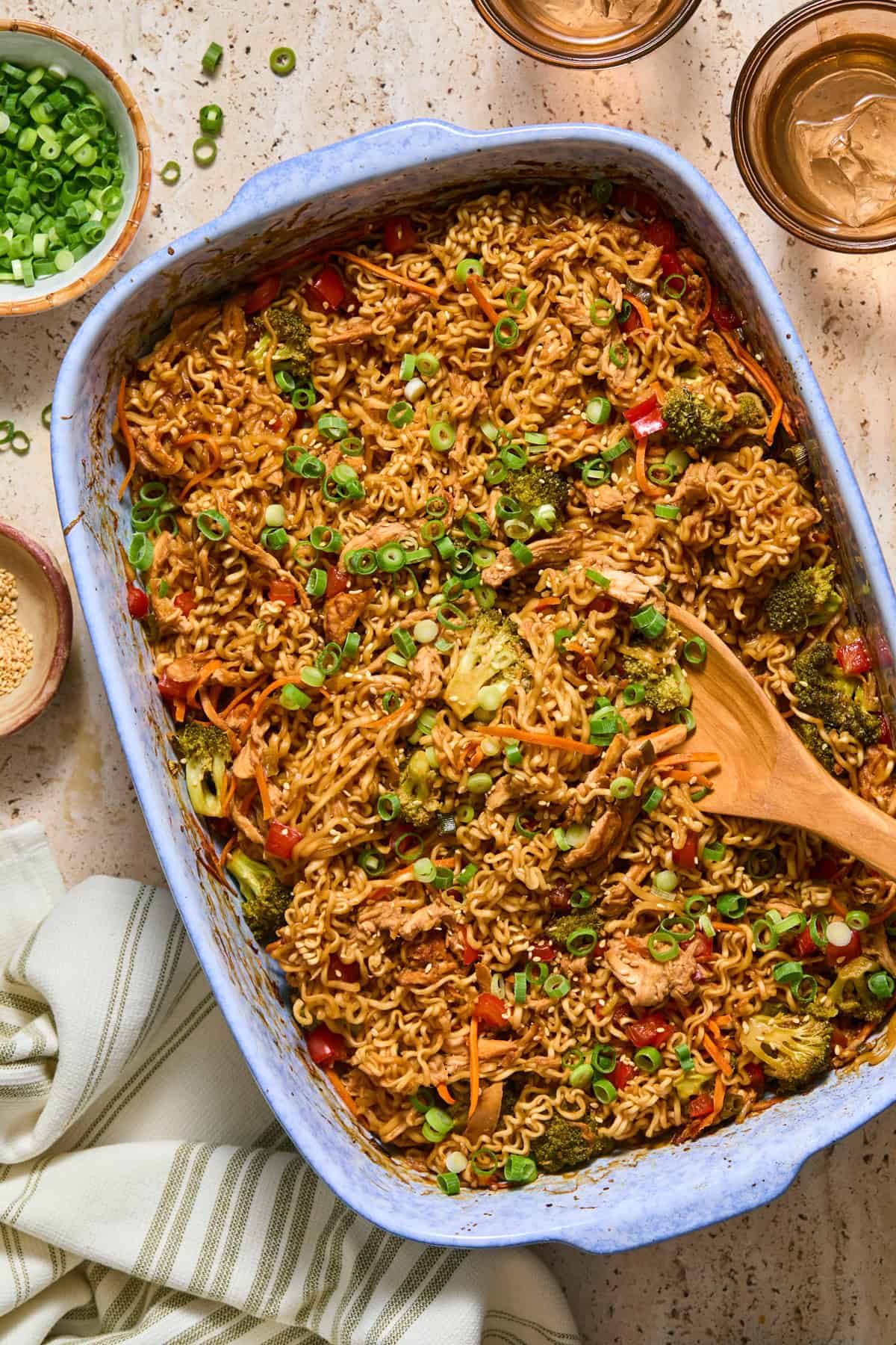 Blue pan with chicken and ramen bake and wooden spoon scooping in.