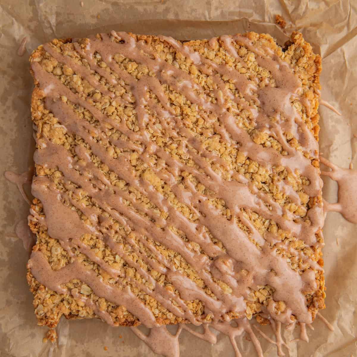 Cinnamon drizzle over oatmeal crumb bars on parchment.