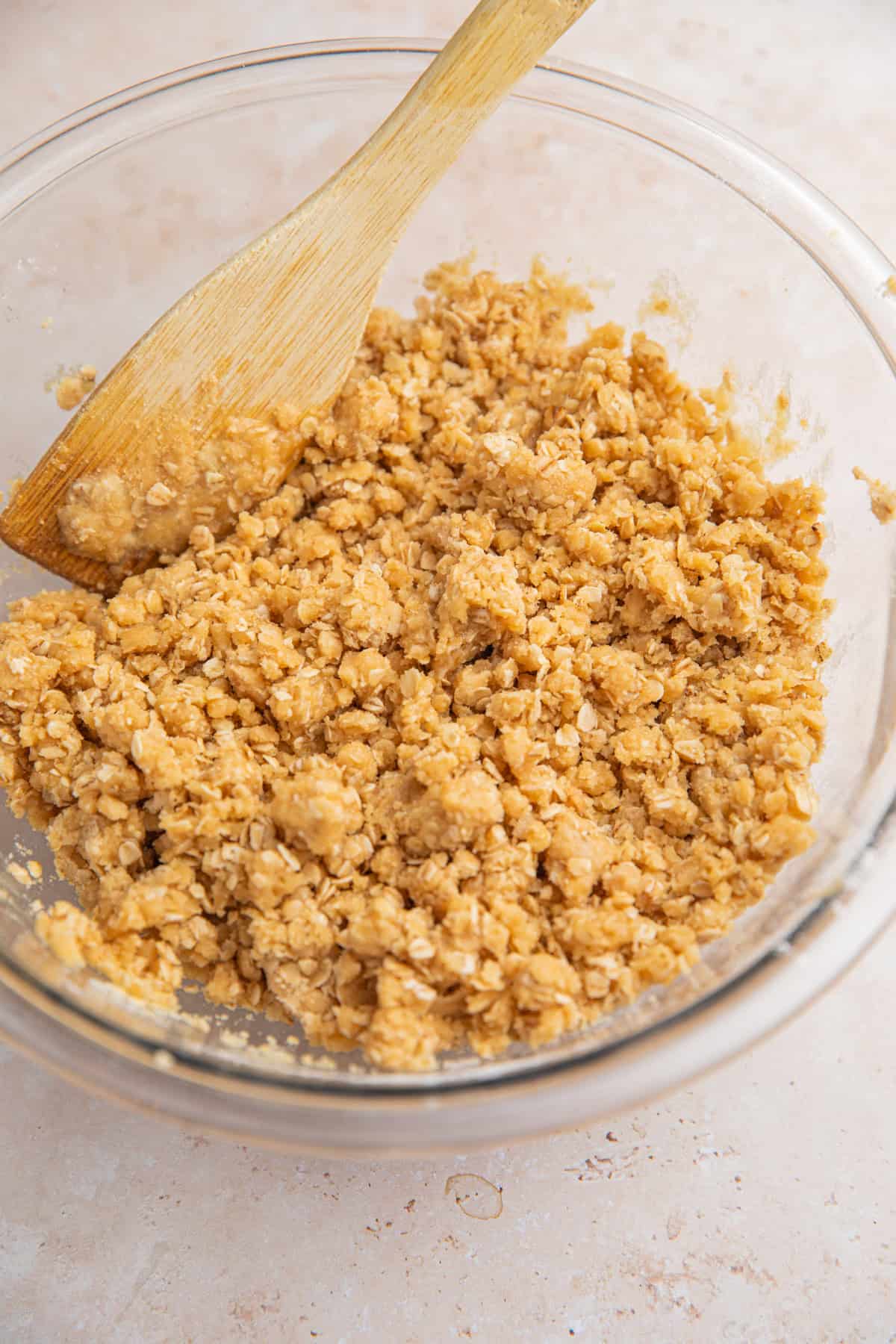 Crumble oat mixture in bowl with spoon.