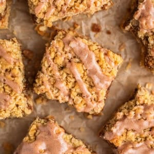 Brown sugar cinnamon oatmeal bars with cinnamon icing drizzle on parchment.