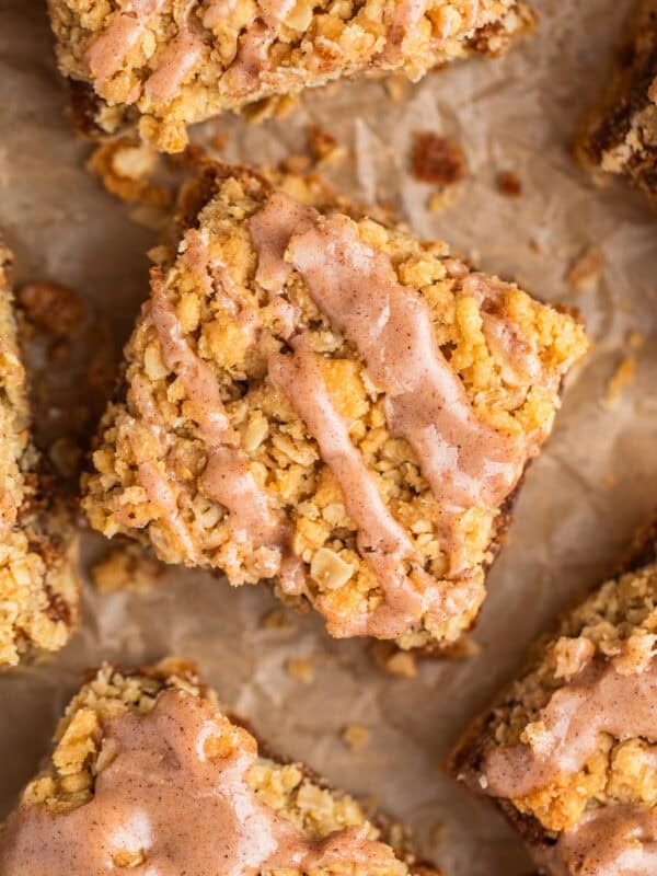 Brown sugar cinnamon oatmeal bars with cinnamon icing drizzle on parchment.