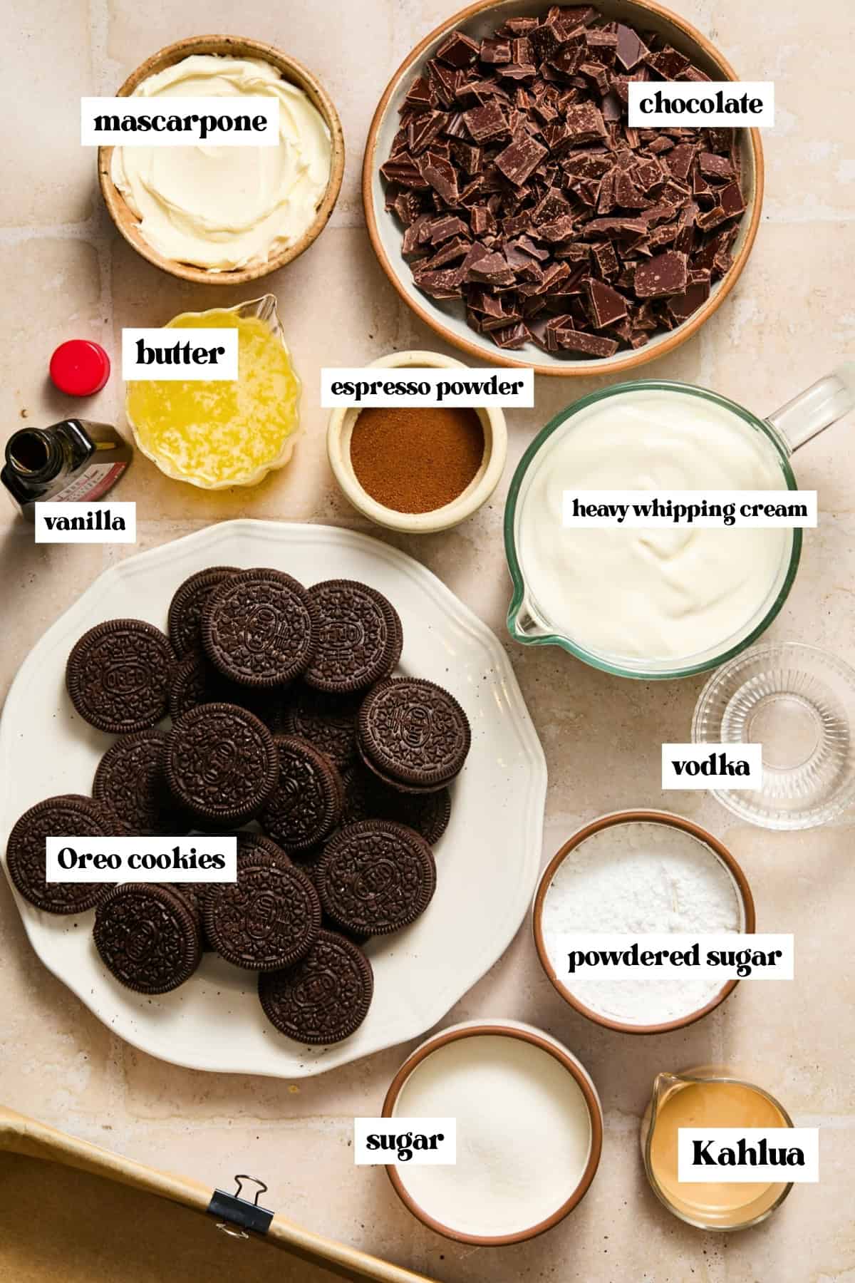 Chopped chocolate, mascarpone, Oreos and other ingredients labeled on surface.