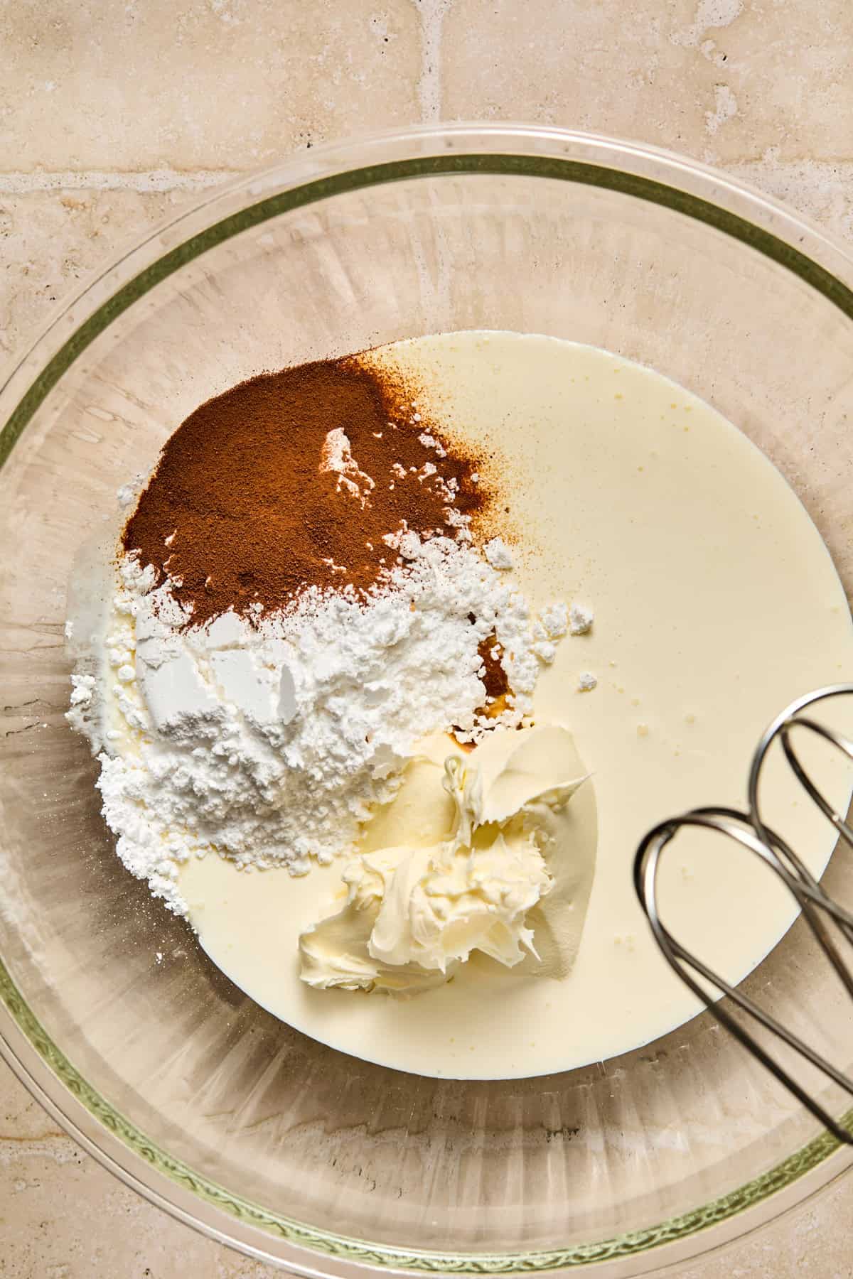 Espresso powder, mascarpone, whipping cream and powdered sugar in bowl.