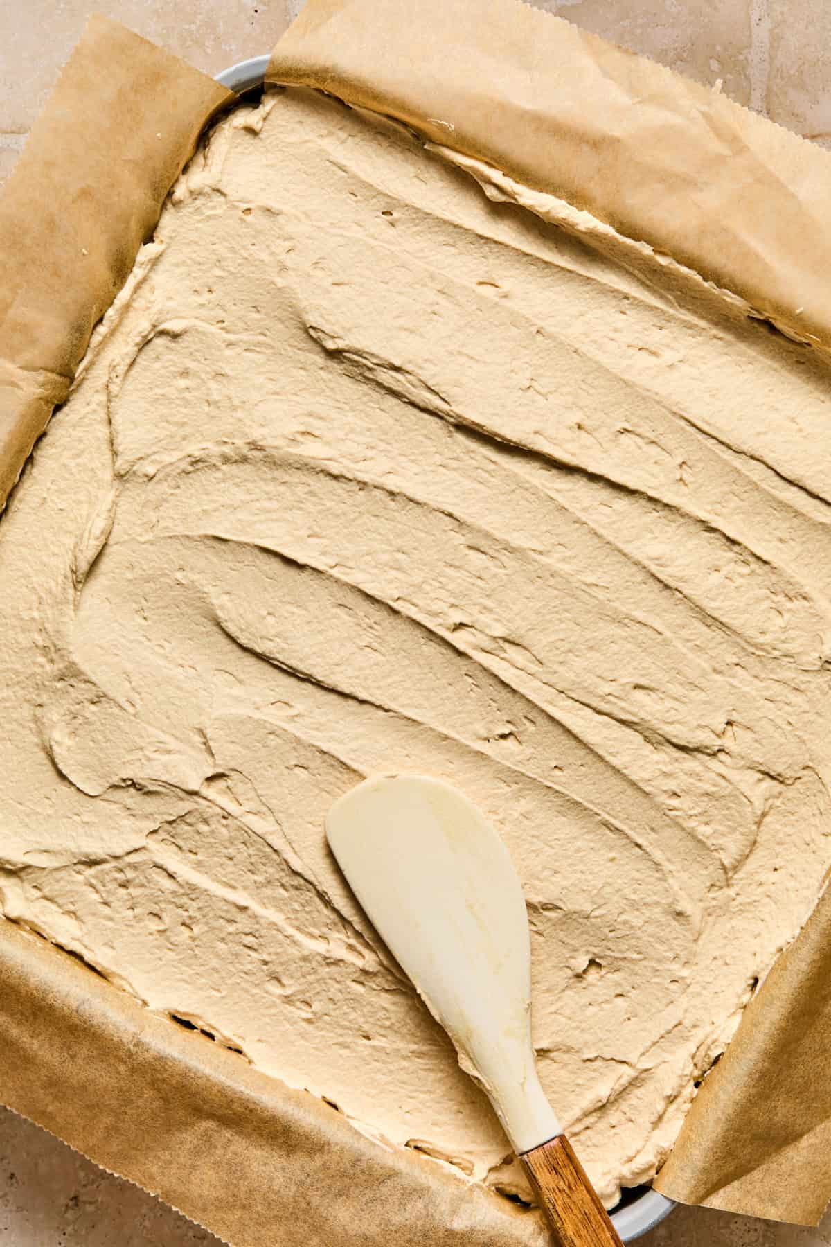 Mascarpone espresso whipped cream being spread over chocolate layer.
