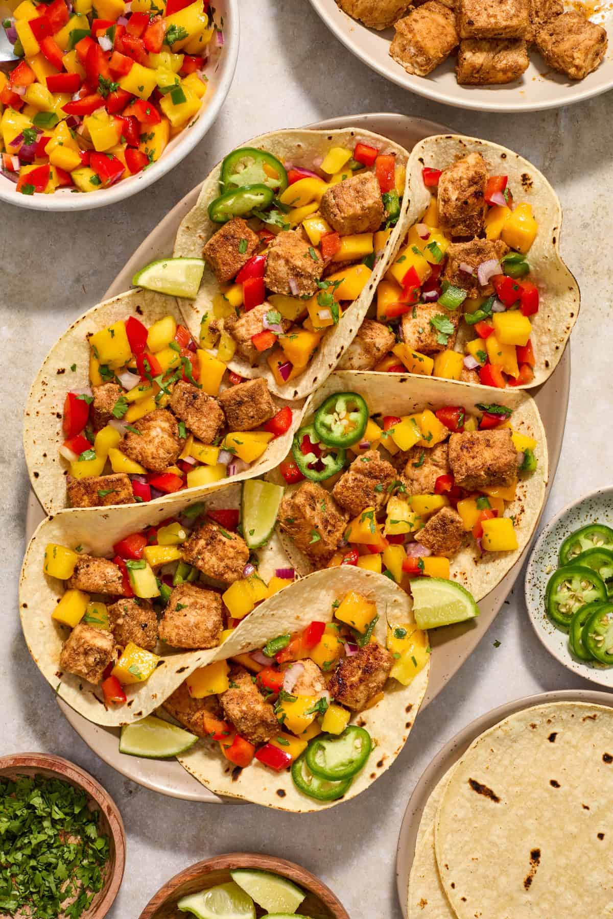 Serving platter with fish tacos topped with mango salsa.