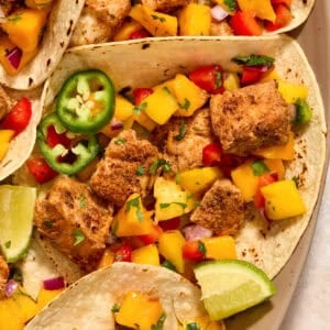 Mahi mahi tacos with mango salsa and lime wedges.
