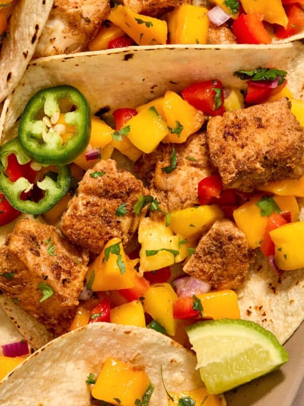 Mahi mahi tacos with mango salsa and lime wedges.