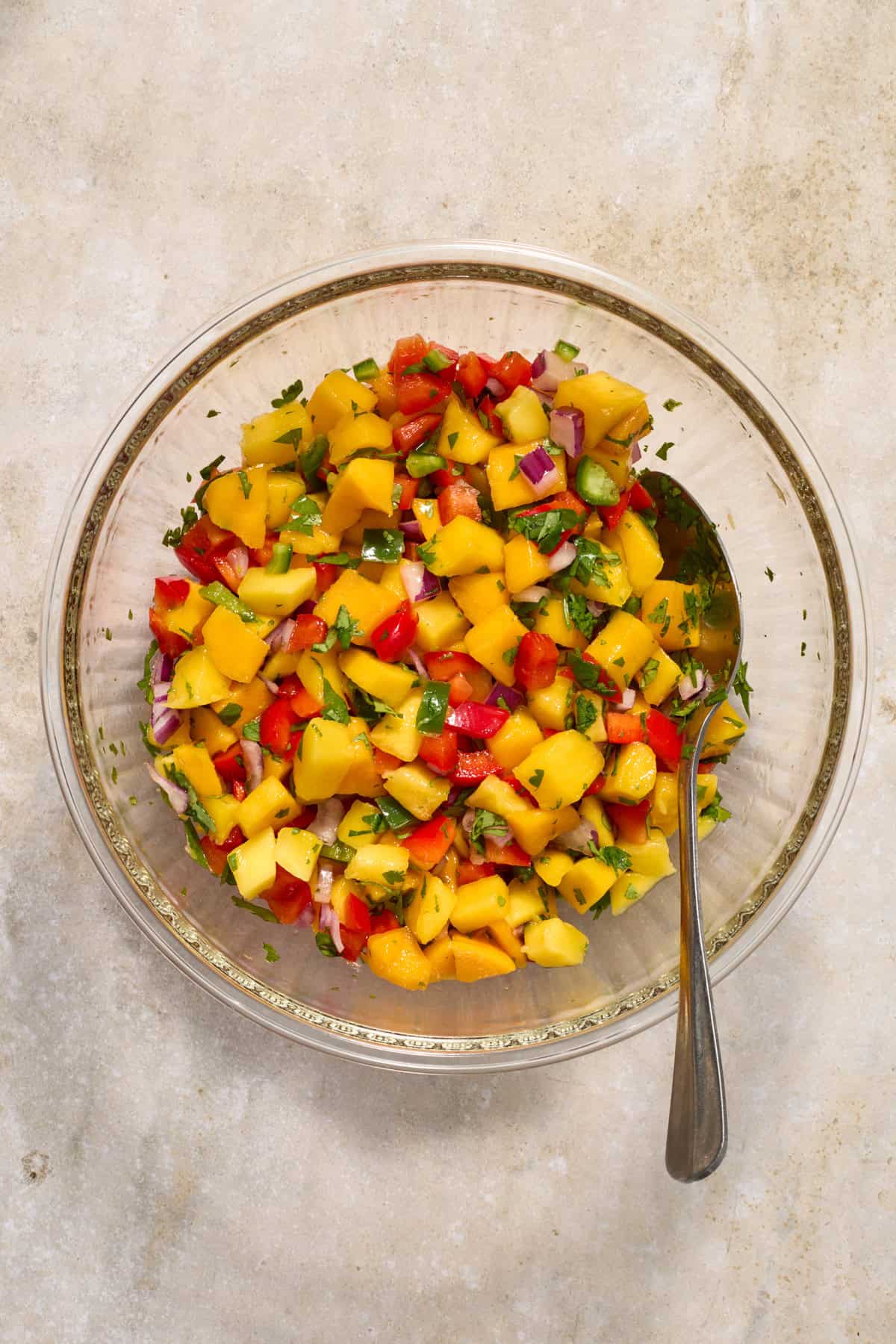 Mango salsa in glass bowl with spoon.