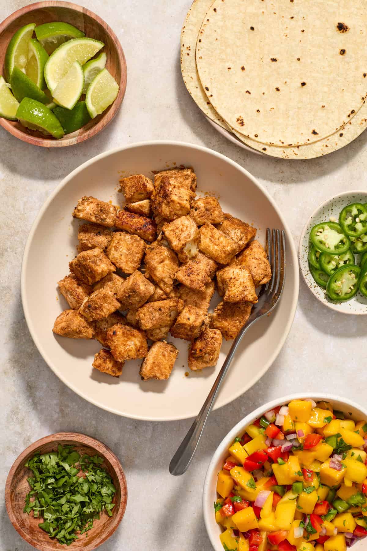 Fish cubed and cooked in bowl with serving spoon.