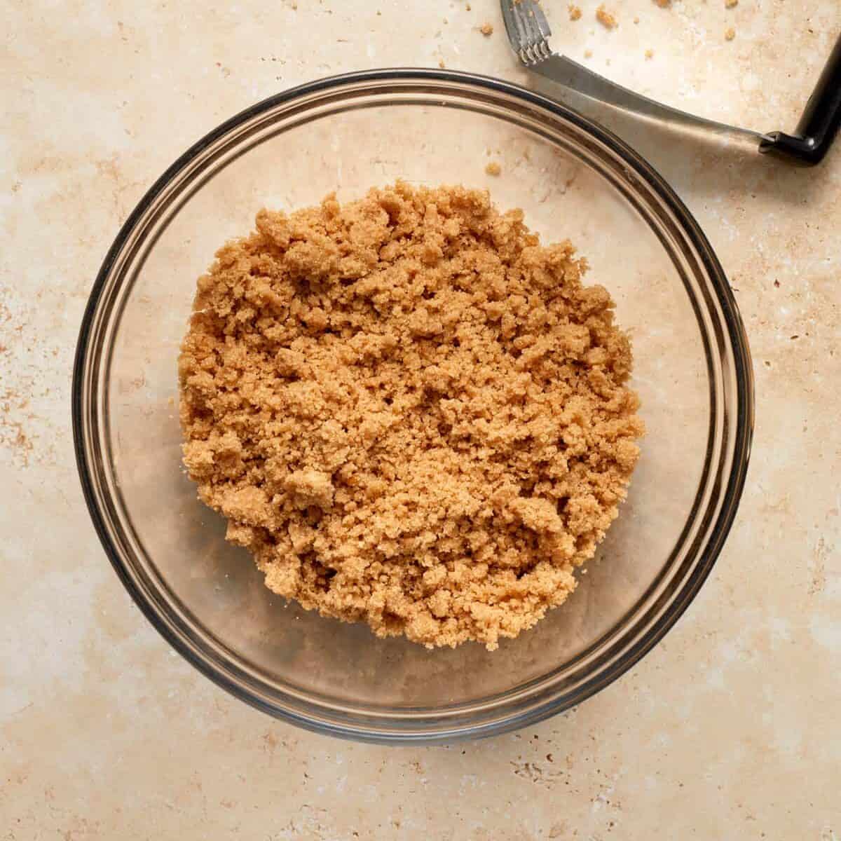 Streusel topping in glass mixing bowl with pie cutter tool.