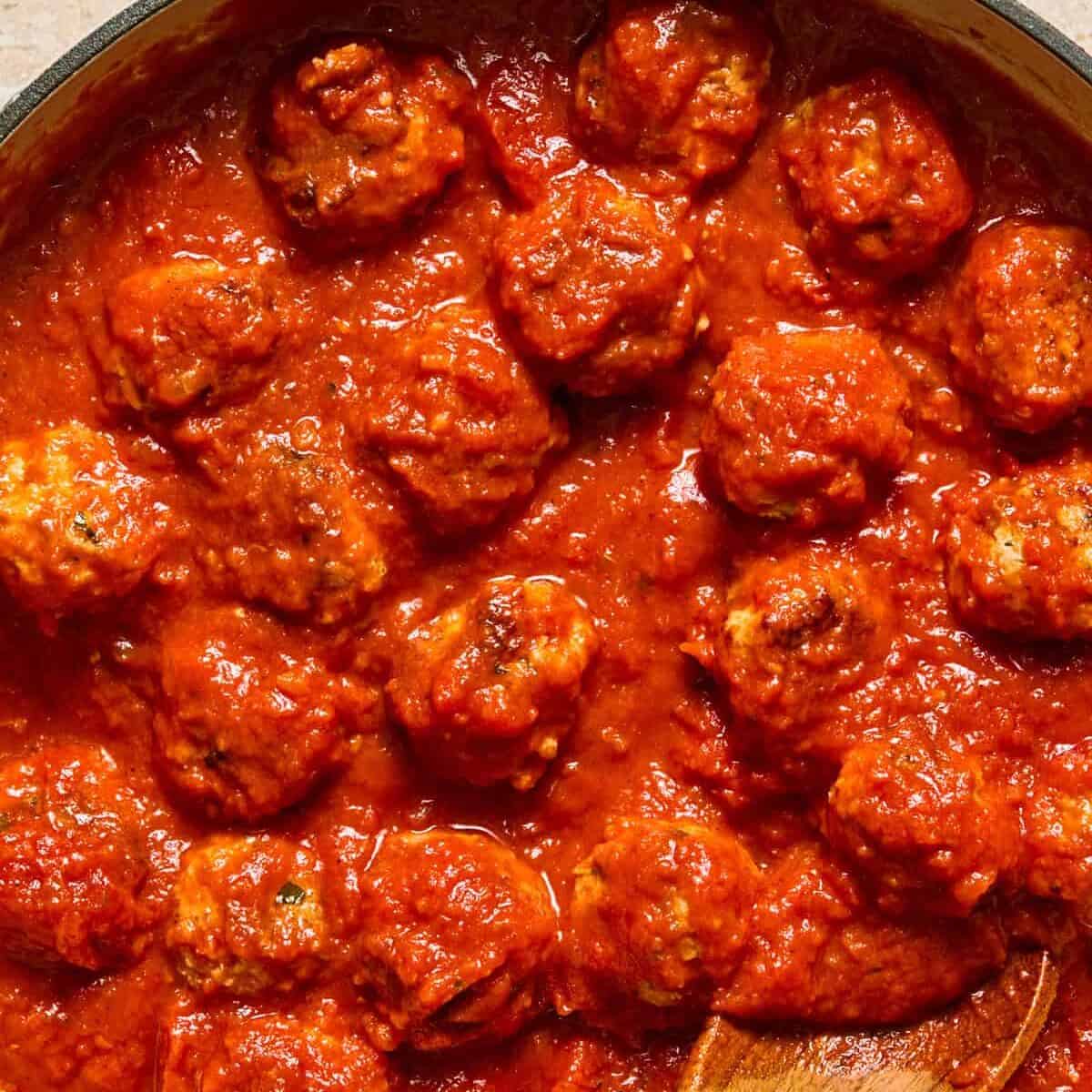 Skillet with simmered ricotta meatballs in marinara.