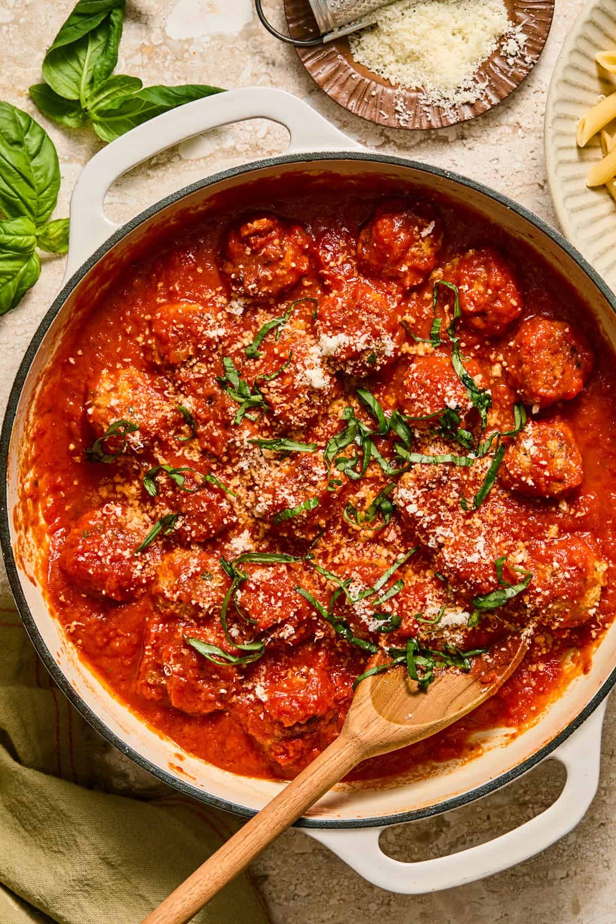 Skillet with meatballs simmered in marinara topped with chopped basil and parmesan.