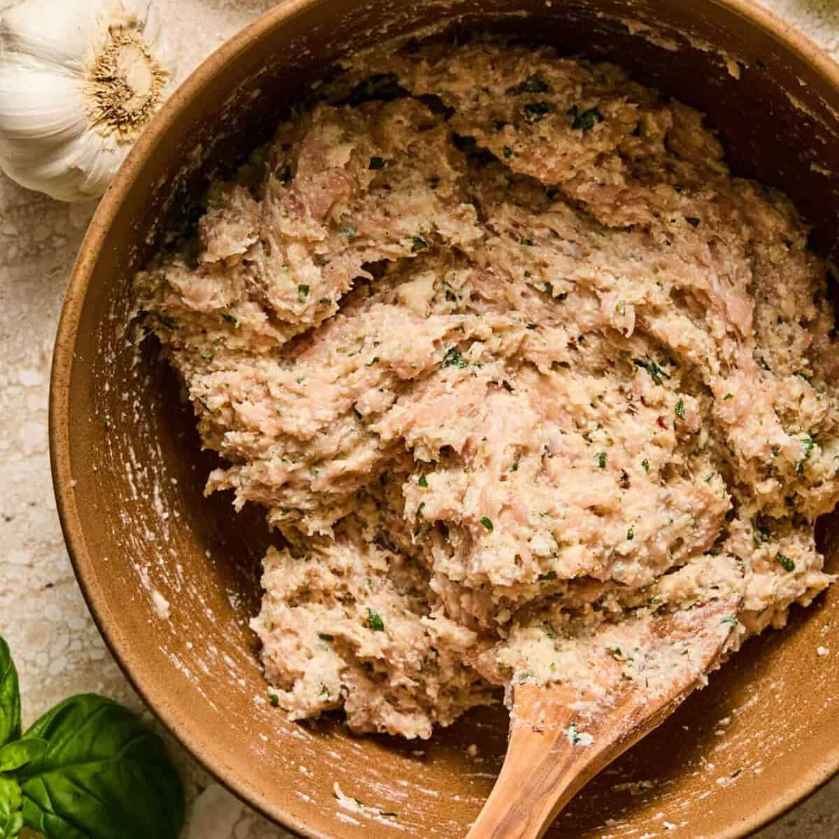 Ricotta chicken meatball mixture in bowl with spoon.