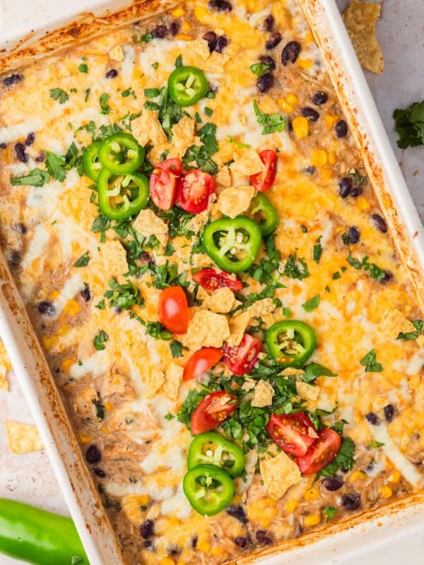 Salsa verde chicken rice bake in pan topped with cilantro, jalapeño and tomatoes.