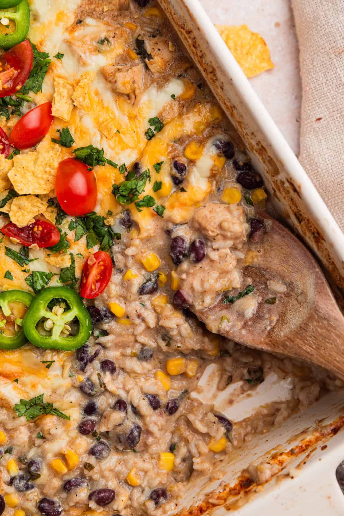 Wood spoon scooping into chicken and rice mixture.