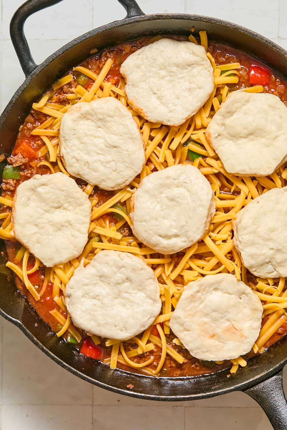 Biscuits and cheese over skillet with sloppy joe mixture.