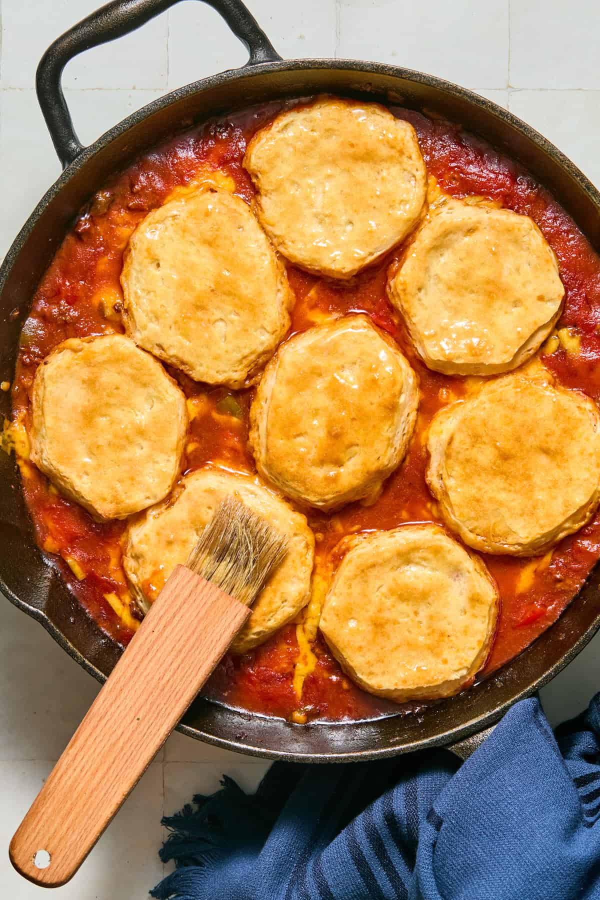 Biscuit tops brushed with butter over casserole in skillet.