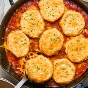 Cheese and biscuit topped sloppy Joe mixture in pan with serving spoon.