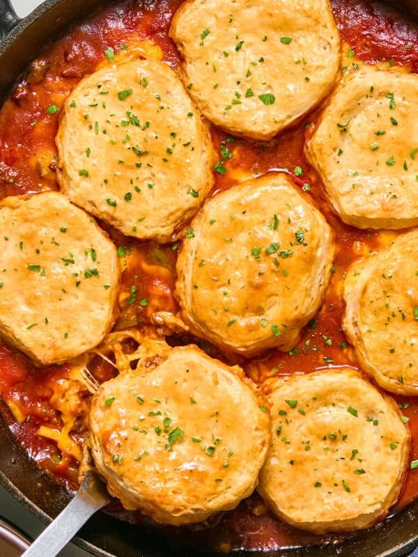 Cheese and biscuit topped sloppy Joe mixture in pan with serving spoon.