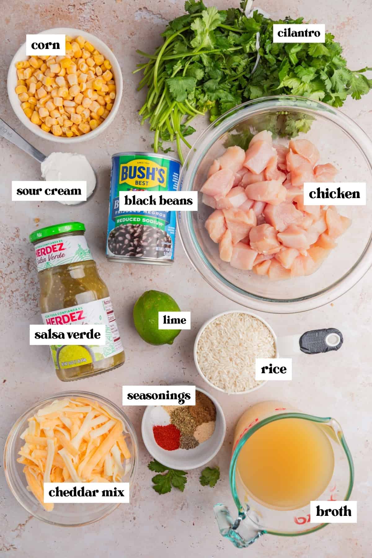 Cubed chicken, cilantro, corn, beans and other ingredients labeled on surface.