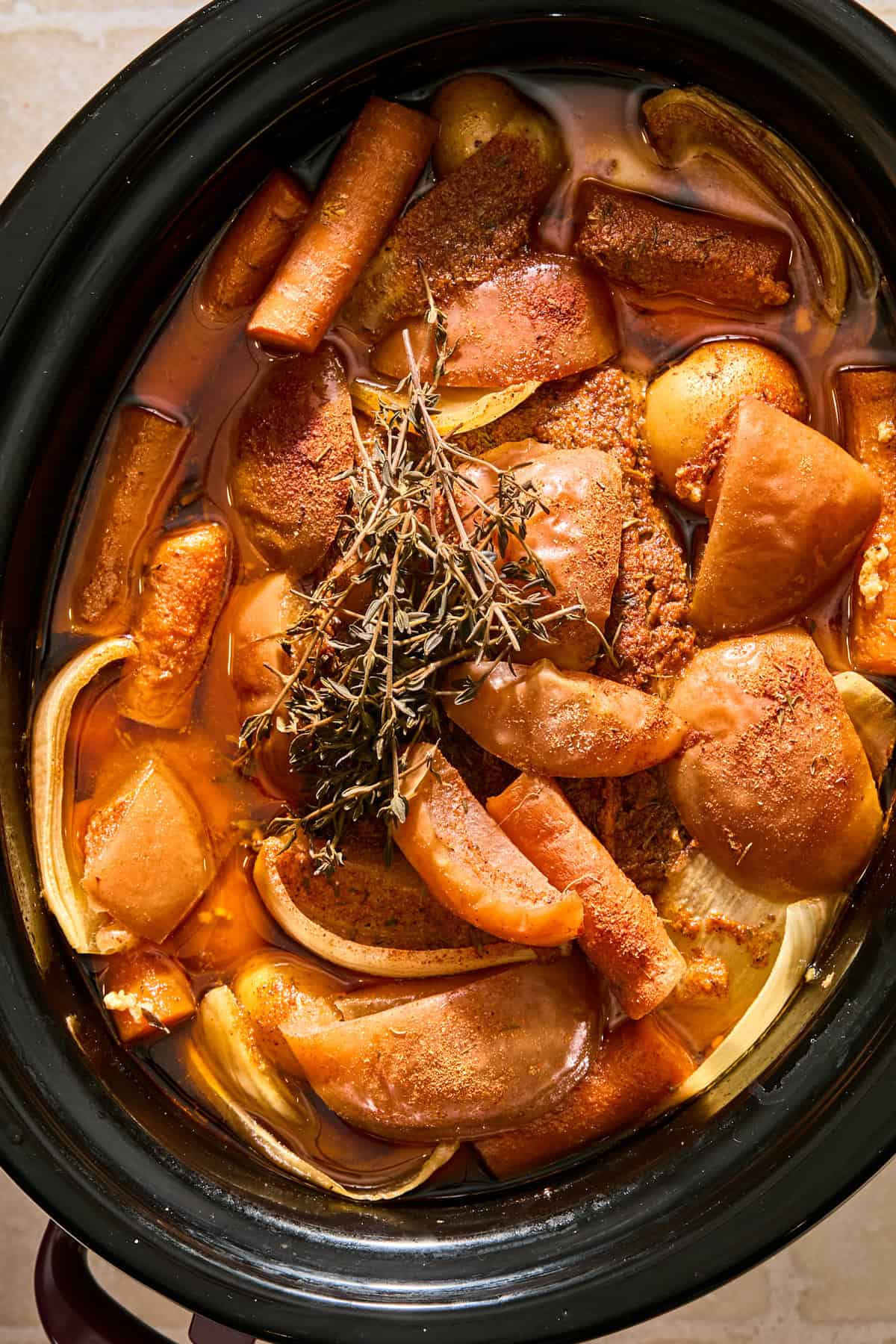 Cooked pork roast in slow cooker with carrots, potatoes and apples.