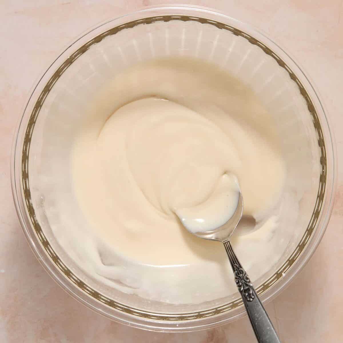 Maple vanilla glaze in bowl with spoon.