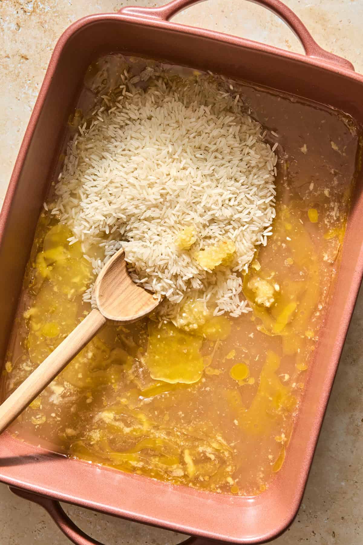 Butter, rice, broth and garlic added to baking dish.