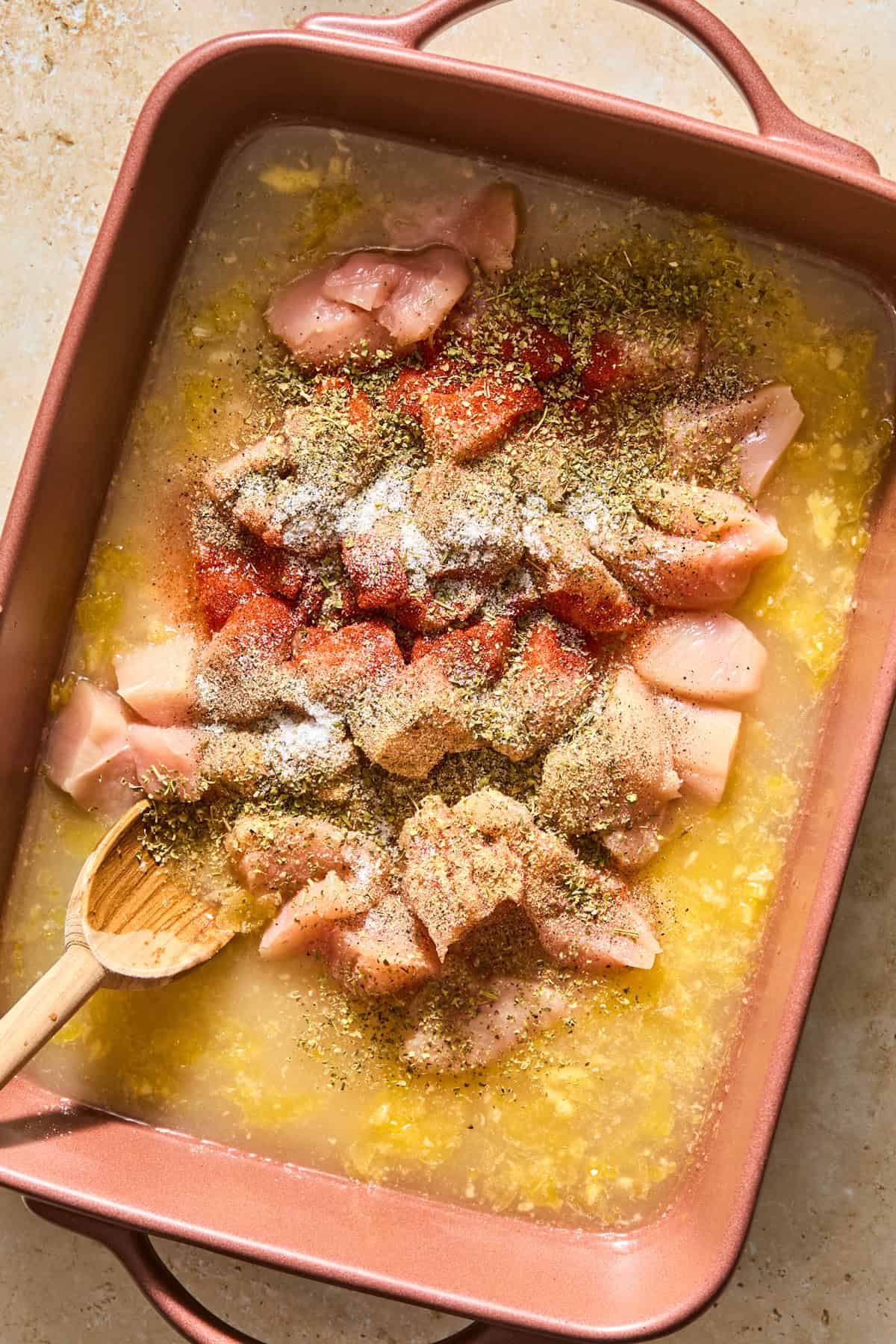 Chicken added to pan with broth and other ingredients and topped with seasoning.