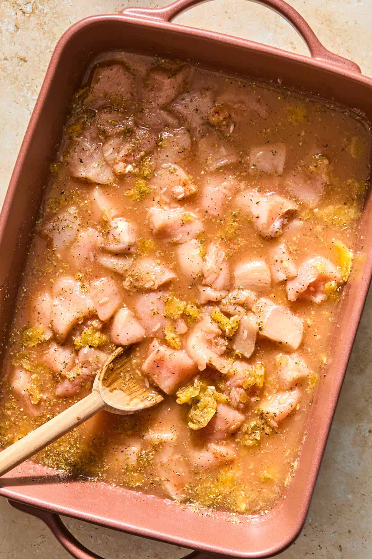 Chicken and rice bake ingredients in pan with wooden spoon.