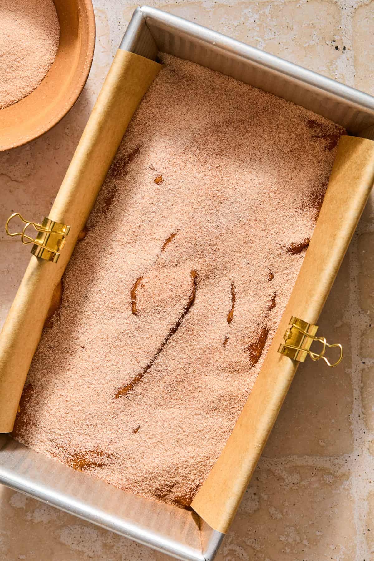 Pumpkin bread batter in bread pan topped with cinnamon sugar mix.