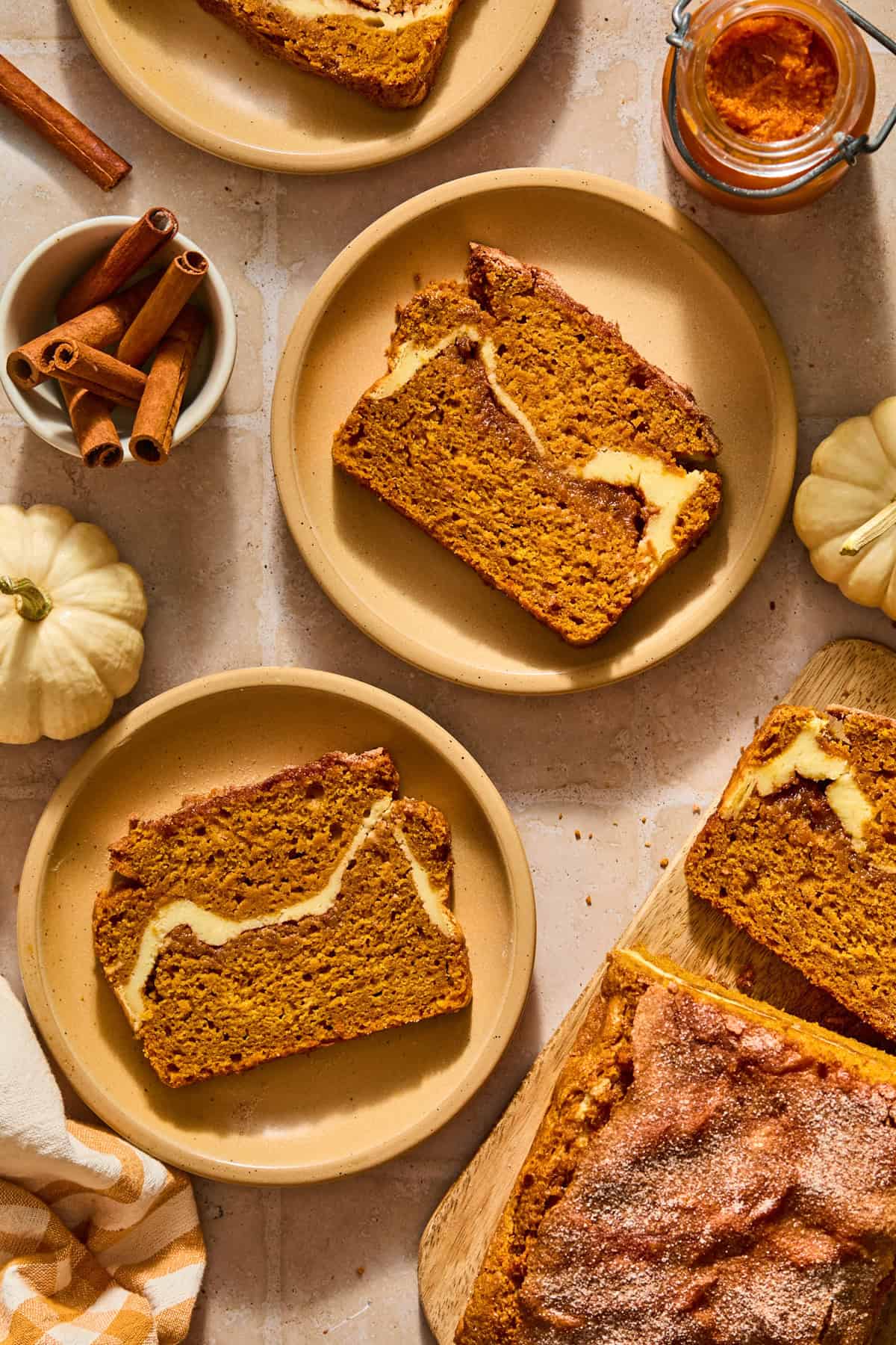 Slices of pumpkin bread with cinnamon sugar and cream cheese swirl on plates.