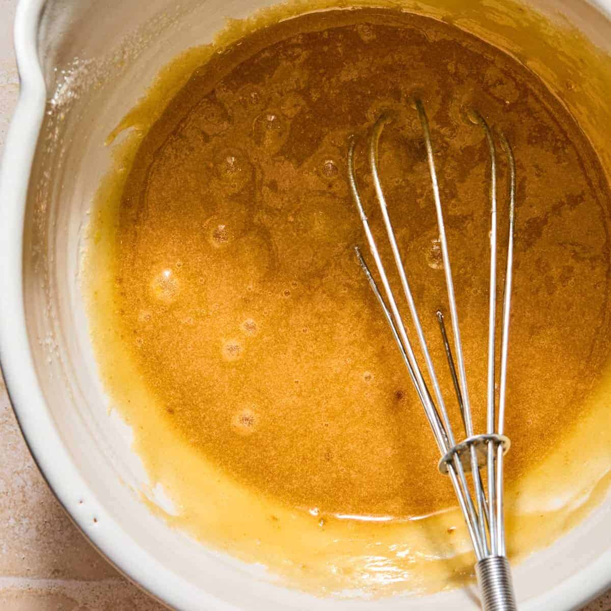 Eggs, brown sugar and regular sugar whisked in bowl.